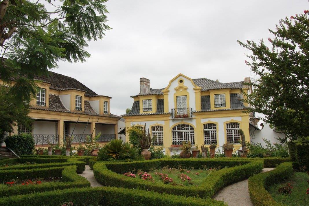 Historic yellow manor house with formal box hedge gardens, Setúbal Peninsula wine estate, Noite na Adega cellar evening experience, Portugal