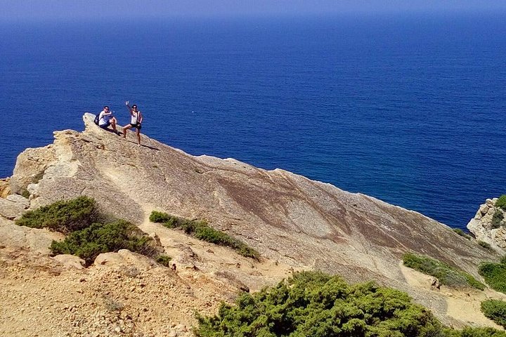 Two visitors on limestone rocky promontory viewpoint overlooking deep blue Atlantic ocean, Serra da Arrabida coastal hike, Arrabida Natural Park, Setubal Peninsula, Segredos da Arrabida
