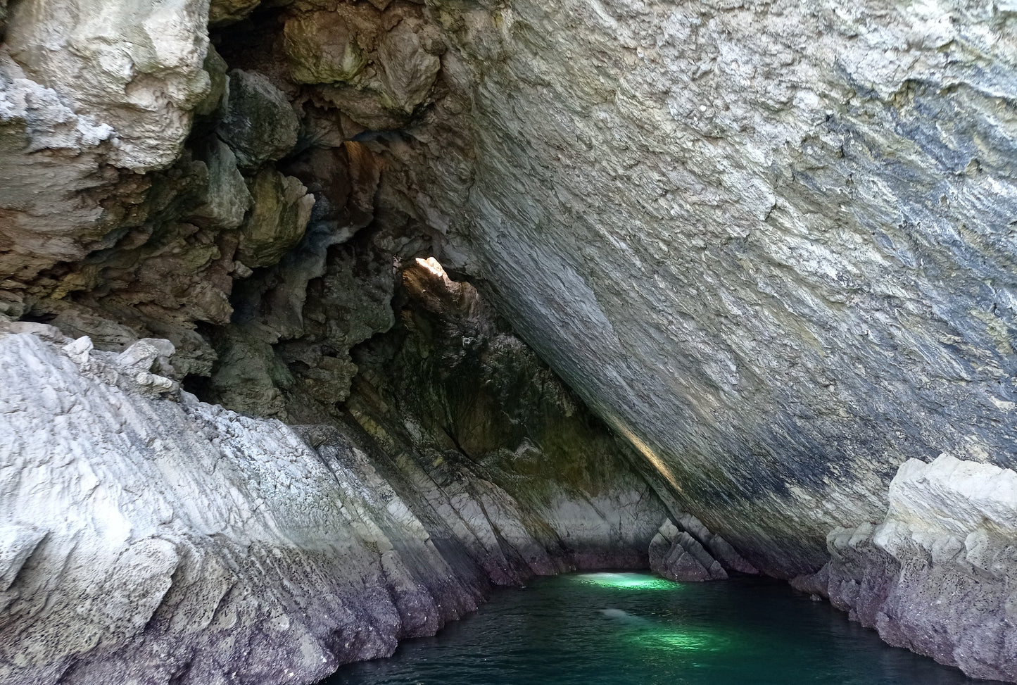 Interior of Boca do Tamboril sea cave with emerald water and limestone walls, Arrábida coastline cave exploration, Setúbal Peninsula