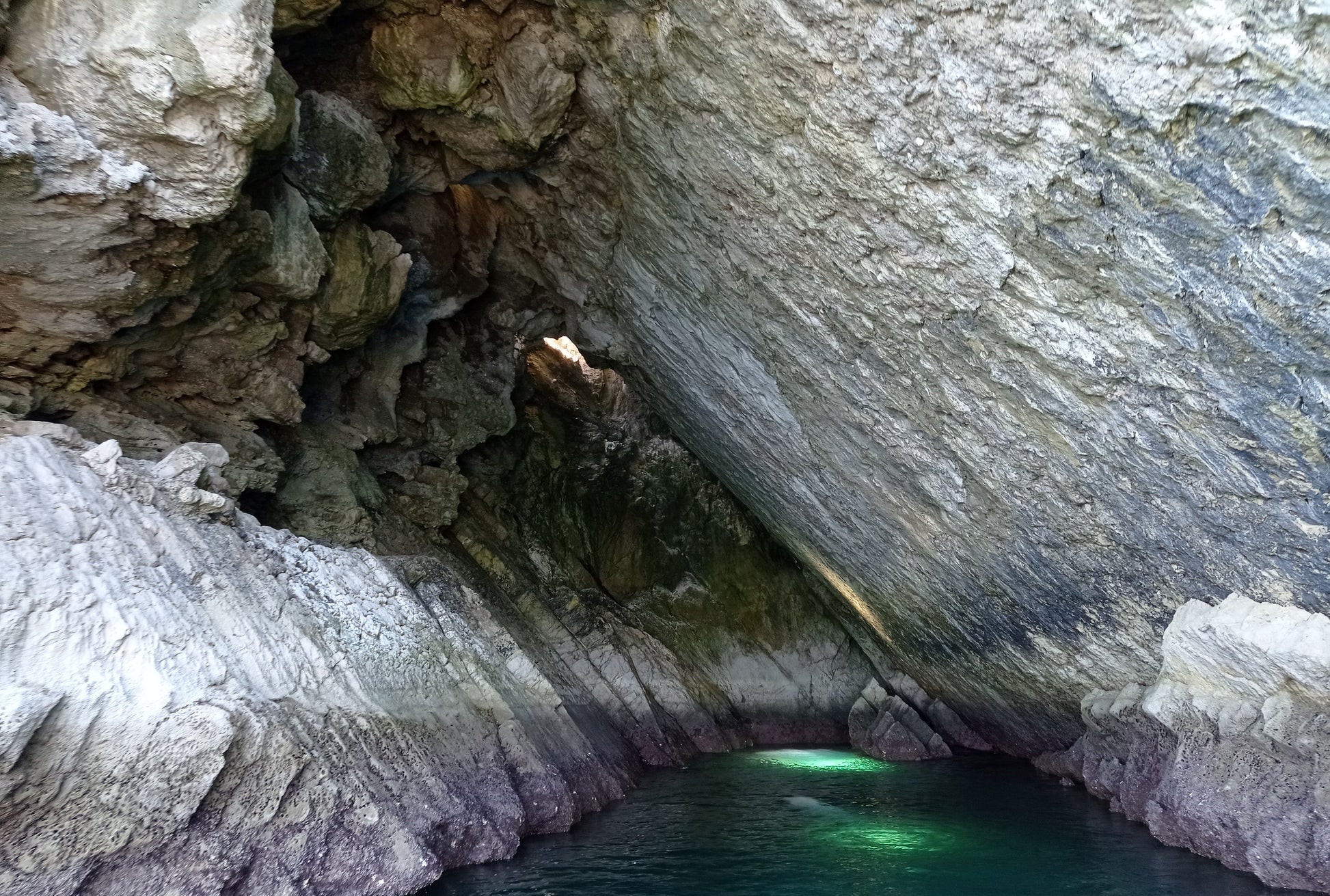Interior of Boca do Tamboril sea cave with emerald water and limestone walls, Arrábida coastline cave exploration, Setúbal Peninsula