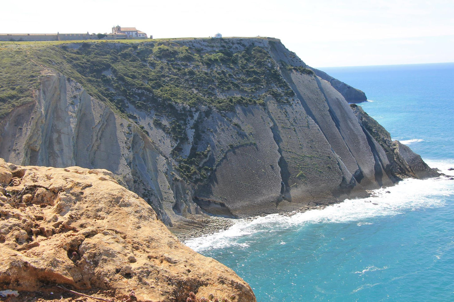 Towering limestone cliffs at Cabo Espichel north face with turquoise Atlantic ocean below and sanctuary on clifftop, Setubal Peninsula, The Untold Weekend Portugal