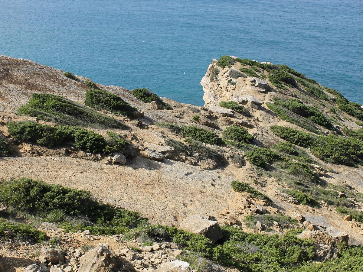 Limestone coastal cliffs with green scrubland overlooking turquoise Atlantic ocean, Sesimbra Safari jeep tour viewpoint, Arrabida Natural Park, Setubal Peninsula, The Untold Weekend