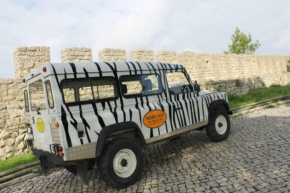 Sesimbra Safari vintage Land Rover with zebra stripe livery parked by historic castle stone wall, Sesimbra, Setubal Peninsula, The Untold Weekend